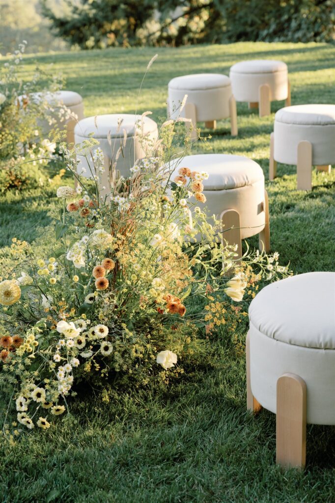 Wild, garden-style floral arrangement beside wine country ceremony seating.